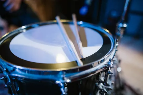 Close-up macro of a snare drum and drumstick mid-strike